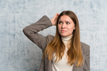 Fototapeta premium Young woman over grunge wall having doubts and with confuse face expression