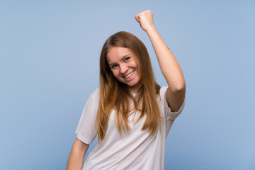 Young woman over blue wall celebrating a victory