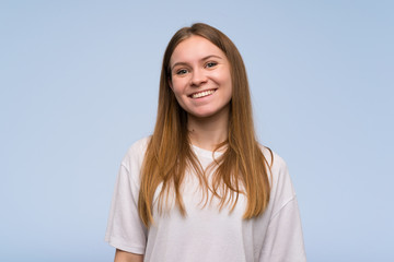 Young woman over blue wall smiling