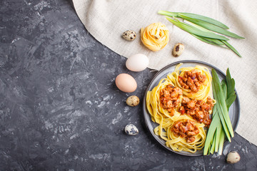 Tagliatelle bolognese pasta with minced meat on a black concrete background.