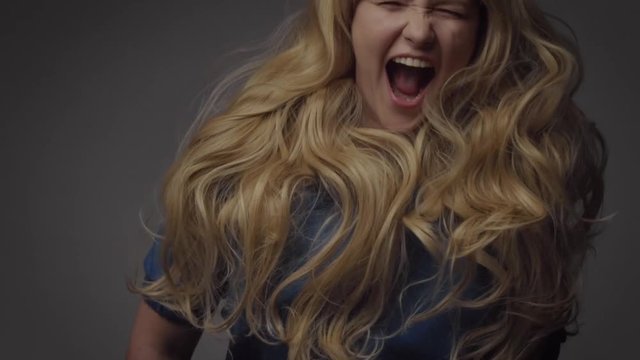 nordic blond model in studio with dramatic top lightumping and her ling curly hair spring Happy smiling laughing screaming Stop motion from 120 fps