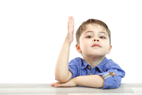 little boy of preschool age raises his hand to answer the question or ask the question. on an isolated background