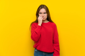 Young woman over yellow wall having doubts