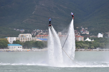 A beautiful show on the water, a sports team flying on flyboards in the sea against the background...