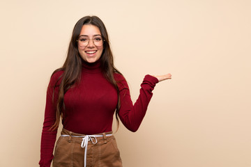 Teenager girl with glasses holding copyspace imaginary on the palm to insert an ad