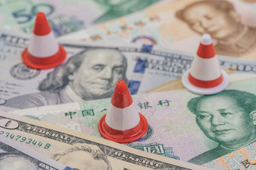 US and China Trade war and tariff reparation concept, small traffic cone for repair and under construction on United States America and Chinese banknotes, financial crisis metaphor