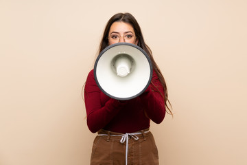 Teenager girl with glasses shouting through a megaphone