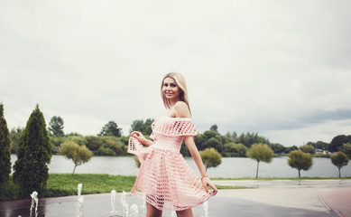 beautiful stylish girl in summer dress walking and posing near fountains