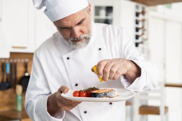 Chef with diligence finishing dish on plate, fish with vegetables