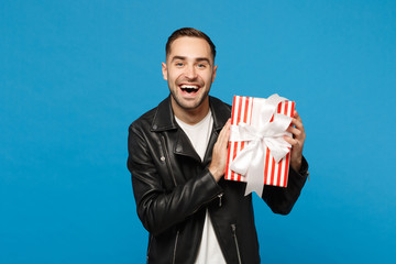 Handsome stylish young bearded man in black leather jacket white t-shirt hold gift box isolated on...