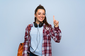 Teenager student girl over isolated blue wall showing and lifting a finger in sign of the best