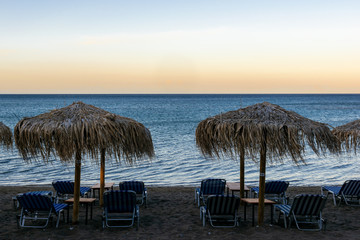 waves and wind on the beach with umbrellas and sunbeds, lounge chairs on sunset