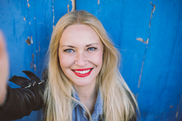 Portrait of smiling blonde woman with blue eyes (making selfie) on vintage background