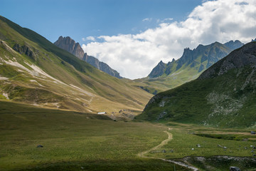 Fototapeta na wymiar Ground road through а beautiful green alpine valley near village of Valloire, Savoie, French Alps.
