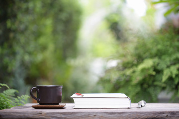 Black coffee cup and notebooks on wooden table at outdoor 