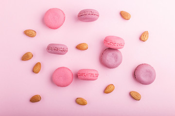 Purple and pink macaron or macaroon cakes with almonds on pastel pink background.