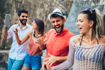 Young happy tourists sightseeing in city. They are having fun listening to music