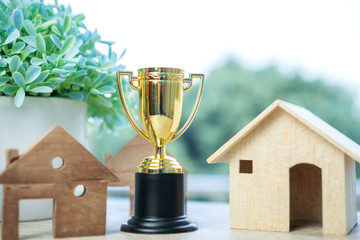Golden trophy winner with house model. Concept of leadership property real estate mortgage in...