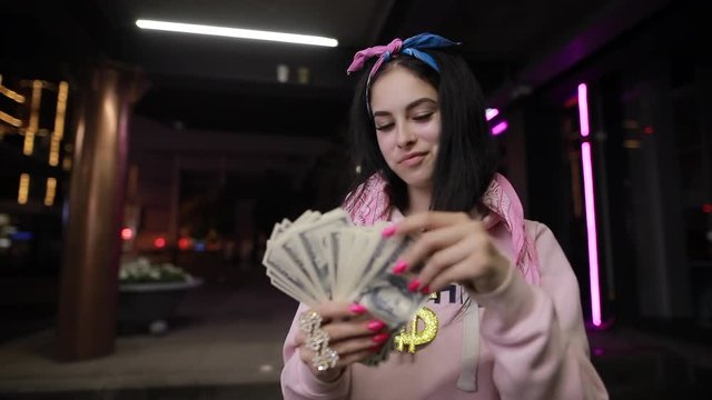 Rich girl play with dollars money at night city