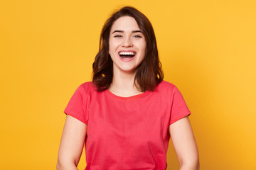 Close up portrait of beautiful cute dark haired girl in good mood wearing casual red tshirt,...