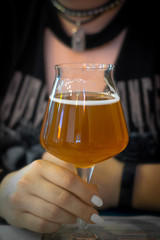 leisure, drinks, degustation, people and holidays concept - close up of woman hand holding glass of draft lager beer