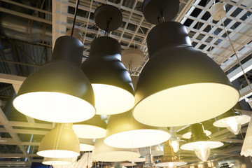 Ceiling lamps in assortment. Lighting store. Beautiful lamps in industrial and loft style are...