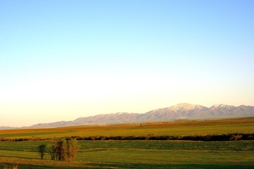 Fototapeta premium Rural area dawn landscape of fields and mountains near Saryozek, Almaty region