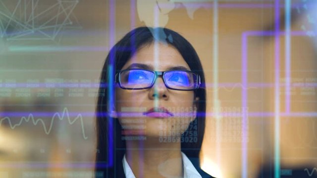 The beautiful businesswoman in glasses on the hologram background