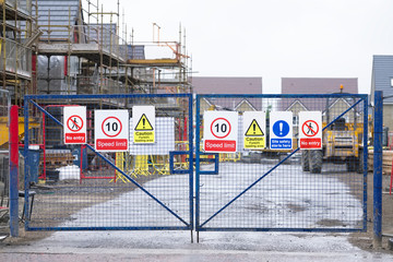 Construction building site entrance gate fence and health and safety signs