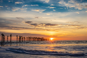 Orange cloud on sea horizon with leading iron poles towards the sun