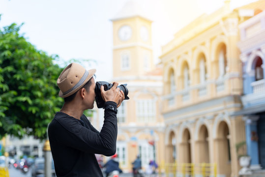 Tourist sightseeing old town ,traveling concept..Asian man holding camera and taking   picture of sino portuguese architecture building on famous walking street  in phuket old town.