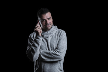 Studio portrait of a man thinking while looking at the camera. Isolated on black background. Horizontal.