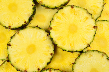 Pineapple juicy yellow slices background. Top view.