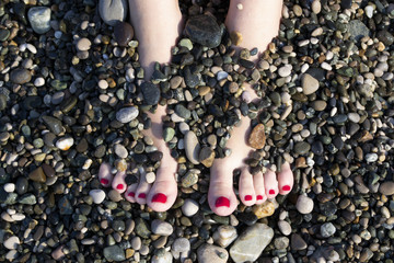 women's feet in sea stones