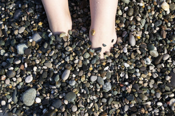 women's feet in sea stones