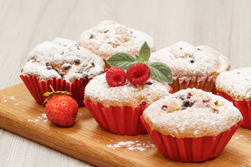 Homemade fruit muffins sprinkled with powdered sugar and mint.