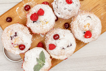 Homemade fruit muffins sprinkled with powdered sugar and fresh raspberries