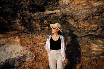 Naklejka premium relaxing time concept with traveler girl posing smile in the sea beach in beautiful sunset time by wear sunglass and hat