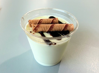 Vanilla pudding dessert covered with chocolate icing in a cup.