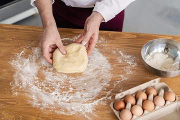 baker making bread , man hands , kneading a dough , cooking coat.