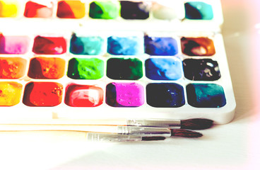 Watercolor paint and brushes well used on white wooden table with copy space for text.