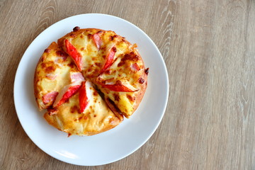 Pizza in a white plate on a wooden table background