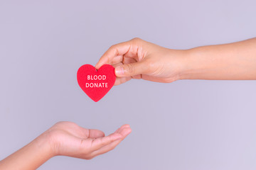 Obraz premium Woman hand gives a red heart to a boy hand for blood donation concept,World blood donor day. Copy space for advertisers.