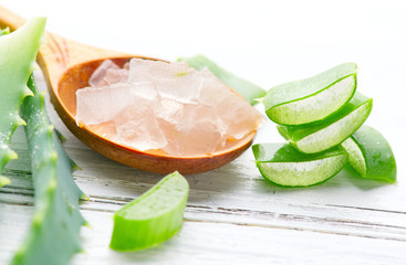 Aloe Vera gel closeup on white wooden background. Organic sliced aloevera leaf and gel, natural...