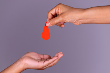 Woman hand gives a red heart to a boy hand for blood donation concept,World blood donor day. Copy...