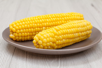 Porcelain plate with boiled corn on a table.