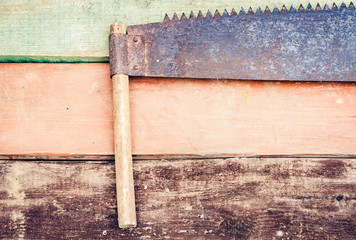 hand saw well used on multicolored wooden boards, retro concept.