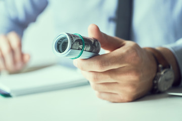 Man giving cutlet of us dollar banknotes and holding cash in hands. Money credit concept. Toned picture.