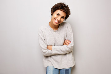 smiling young woman posing against wall with arms crossed