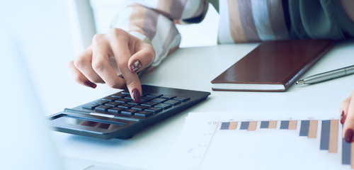 A woman's hand pointing on summary report chart and calculate finance in office close-up.